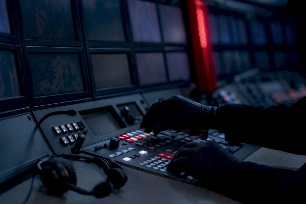 Hands adjusting controls in dark security operations center