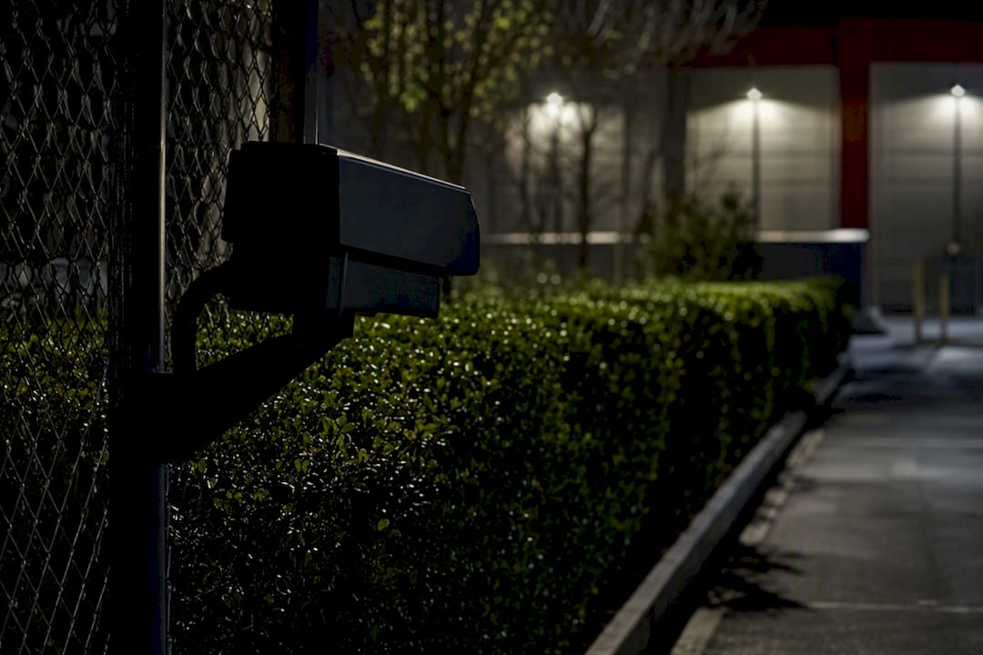 Silhouette of security camera and fence at night